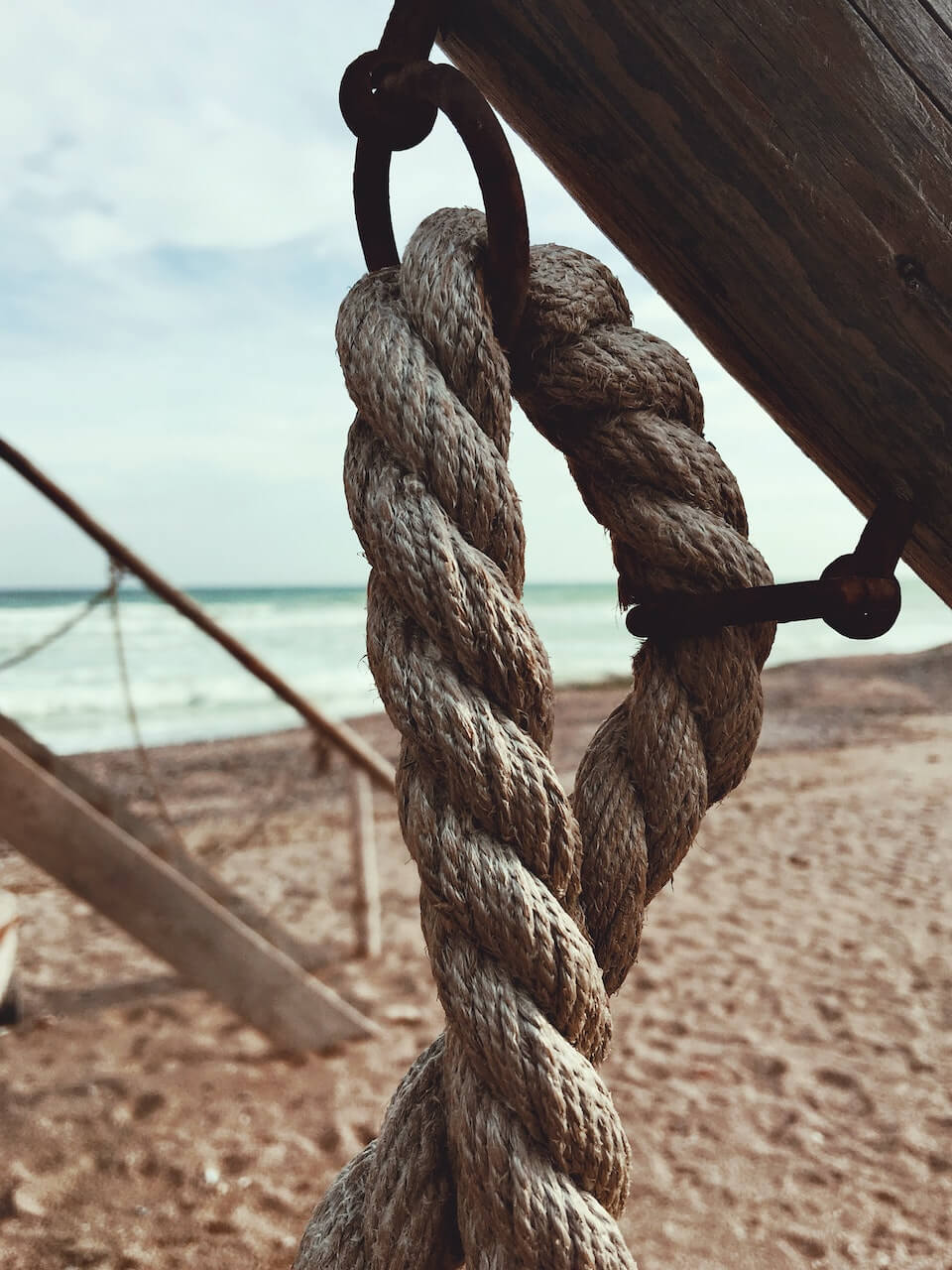 Rope hanging from a wooden pole on the beach.